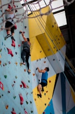 three people climbing on wall