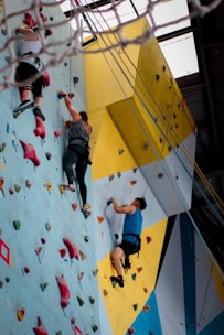three people climbing on wall