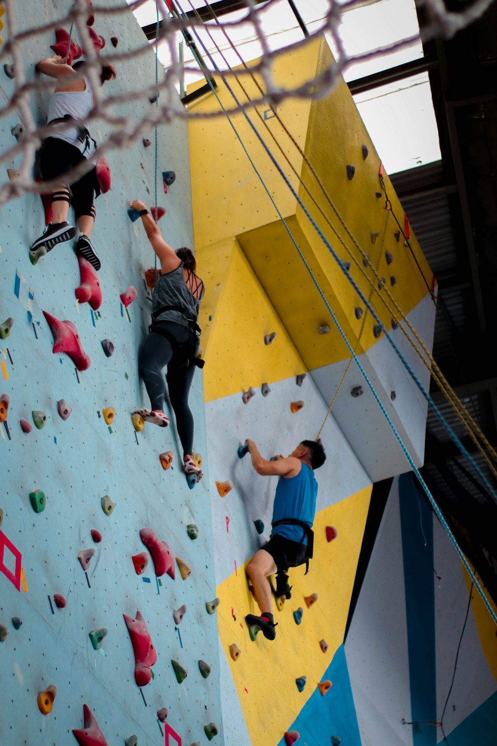 three people climbing on wall