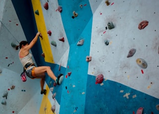 person in white tank top rock climbing