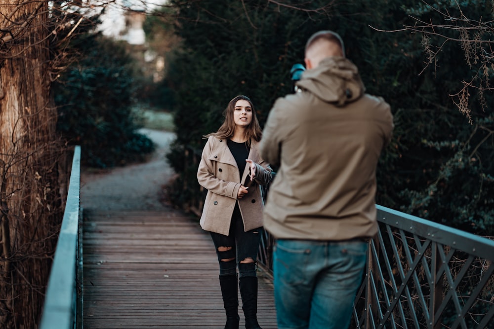 man taking photo of woman on bridge