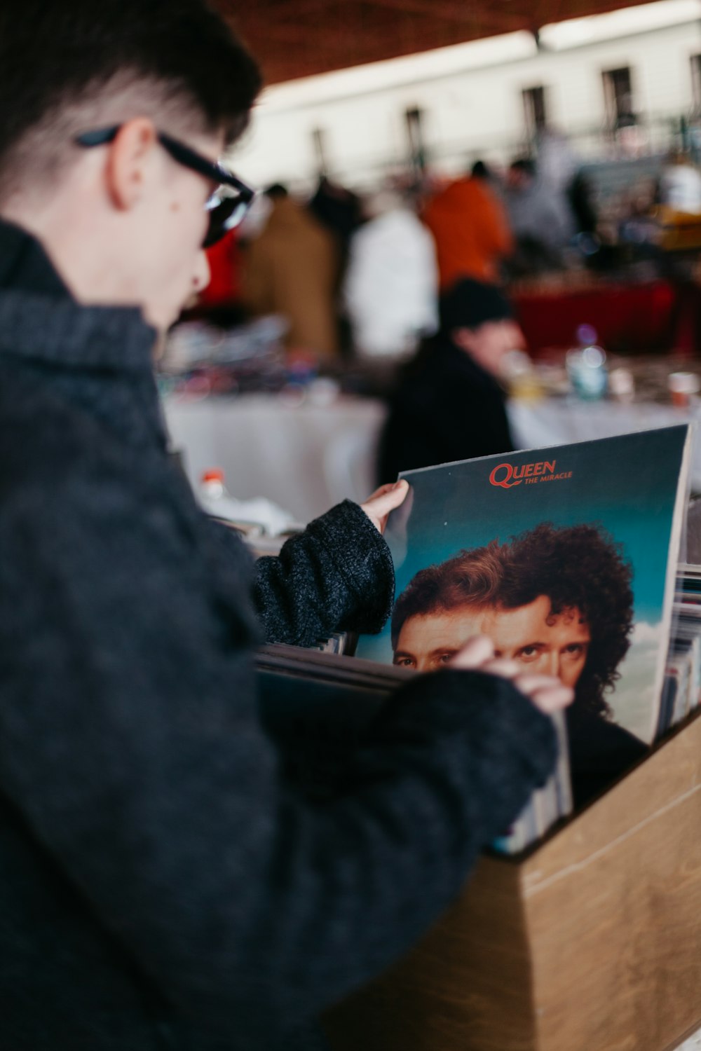 shallow focus photo of man holding vinyl album sleeve