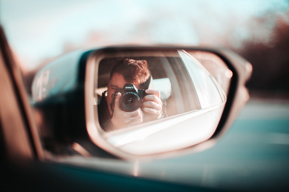 person taking photo of wing mirror