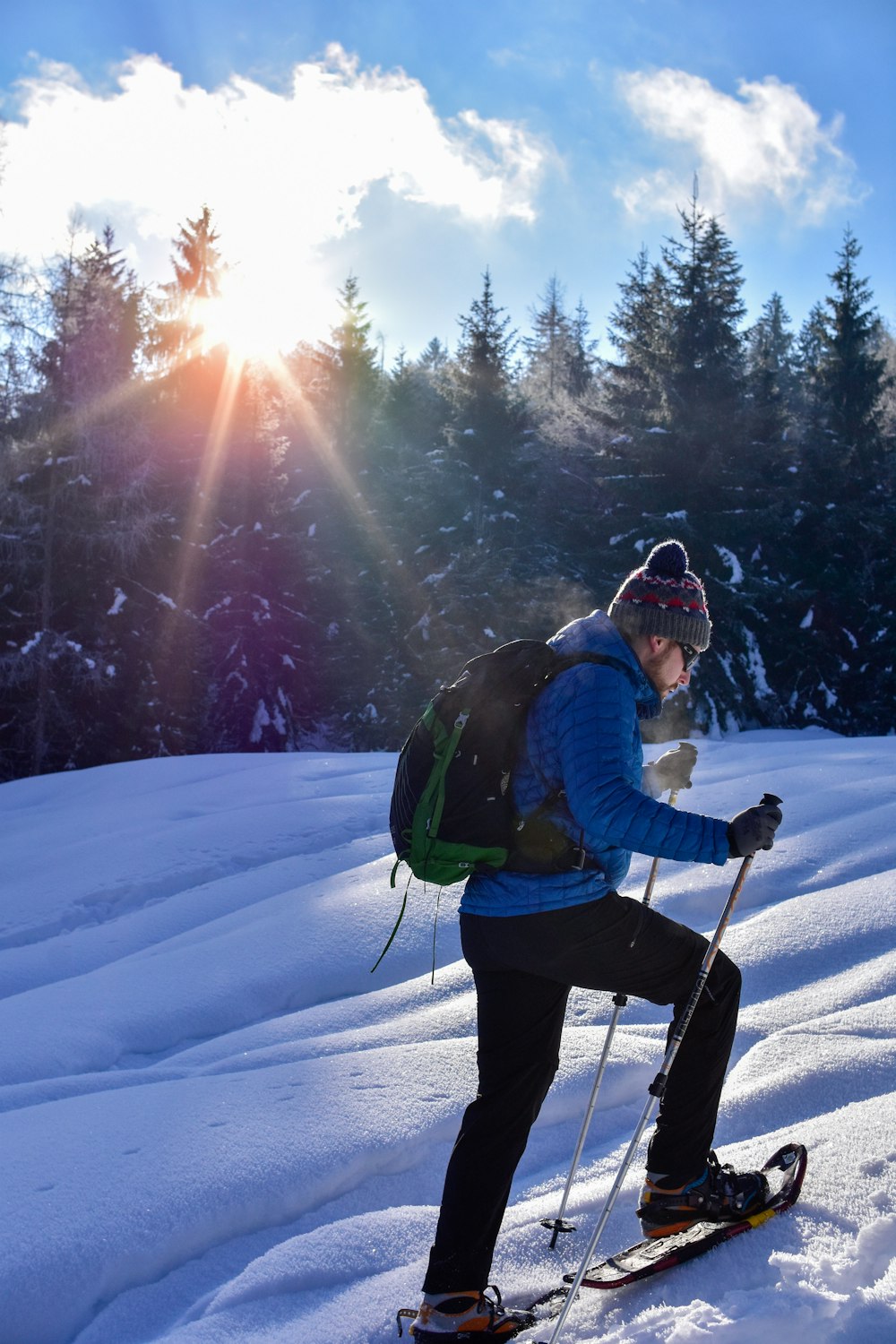 man wearing blue bubble jacket skating on snow under blue and white sky