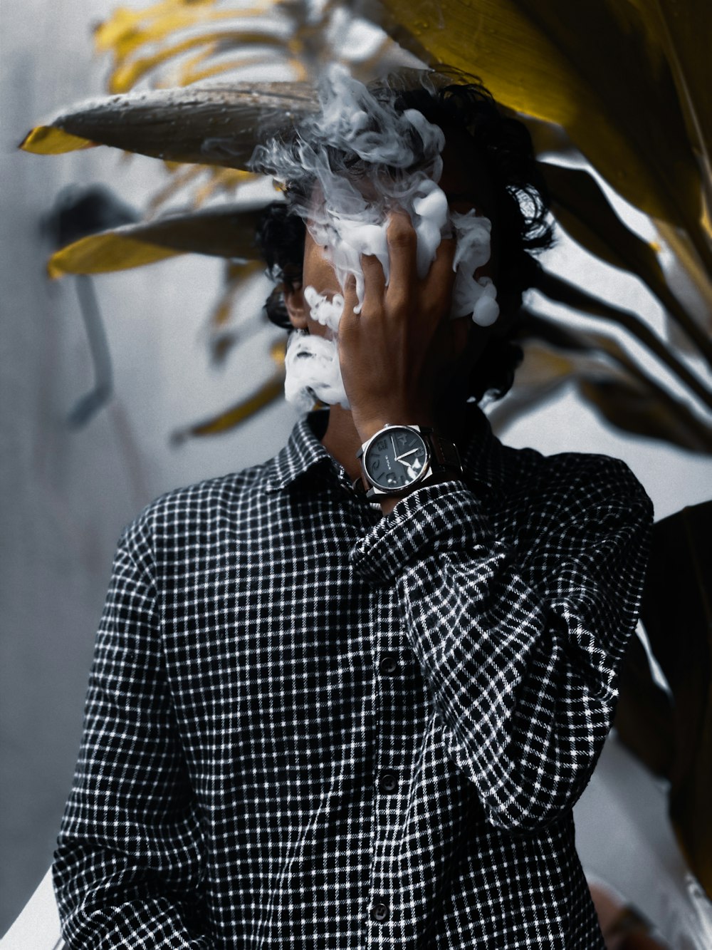 man breathing smoke beside green leaves