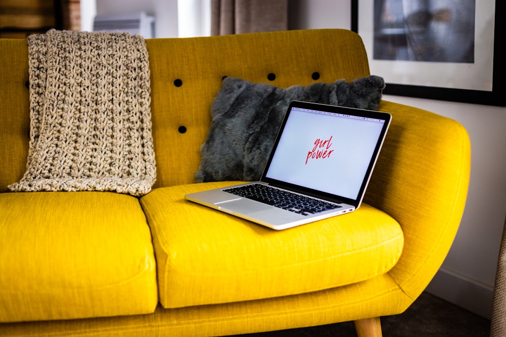 Foto mit flachem Fokus eines grauen Laptop-Computers auf gelber Couch