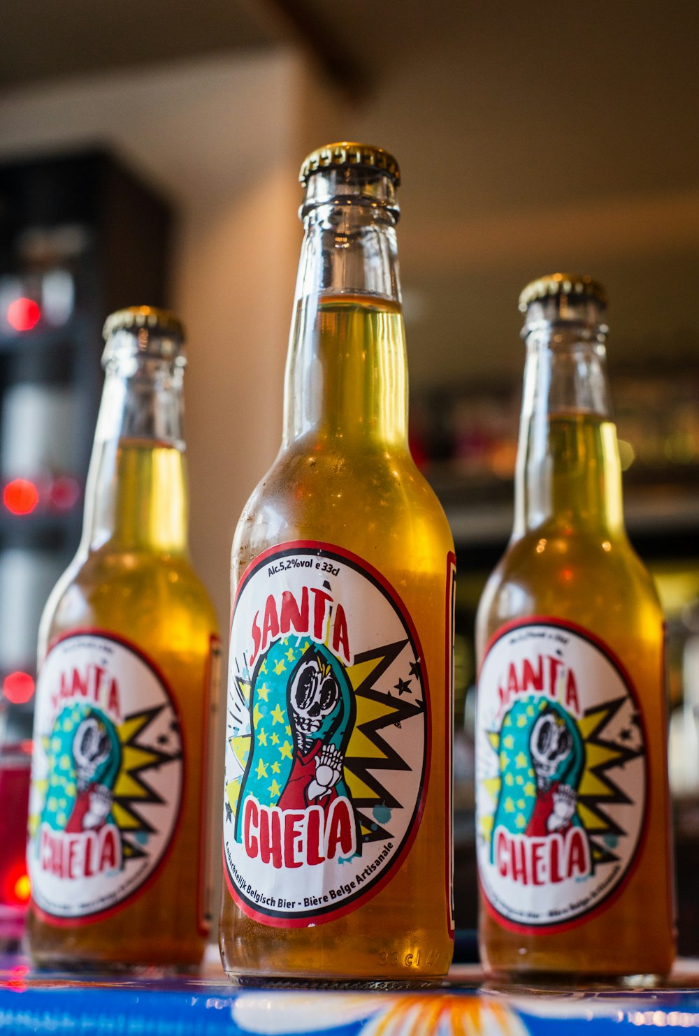 three Santa Chela bottles on red surface