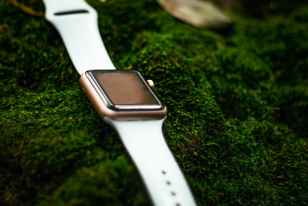 shallow focus photo of gold-colored smartwatch with white sports band strap