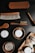 A collection of grooming products is displayed, including various brushes with wooden handles and soft bristles. There are also containers labeled as 'CLEAN + HYDRATE,' 'POLISH,' and 'WAX,' along with wooden bowls holding these products. Natural elements such as nuts or seeds are arranged on a wooden tray.