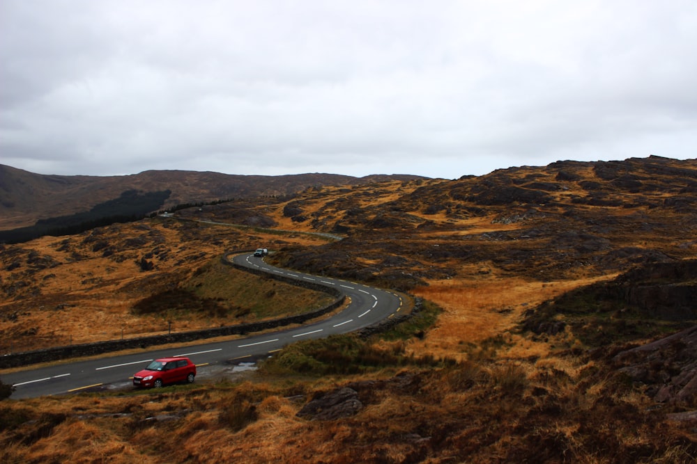 red vehicle parked beside road during daytime