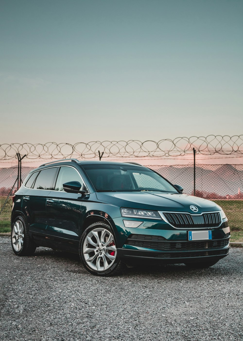 black Skoda SUV parked beside fence