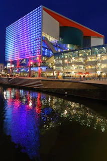 Exterior view of Inovatec Escola building illuminated with blue and green lights reflecting innovation.