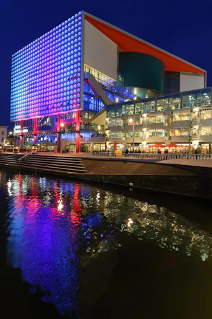Exterior view of Inovatec Escola building illuminated with blue and green lights reflecting innovation.