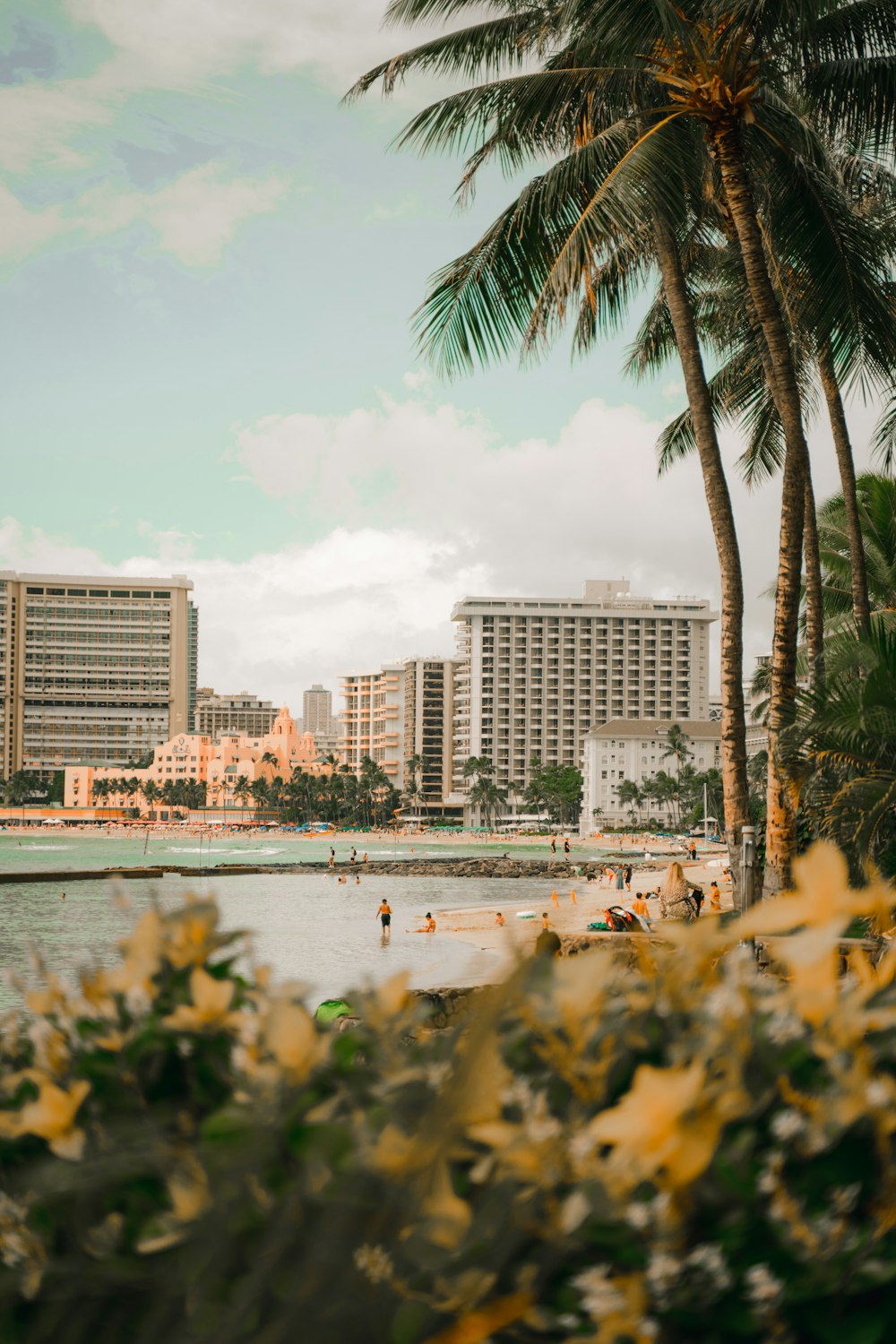 people on beach near hotels and buildings under blue and white sky