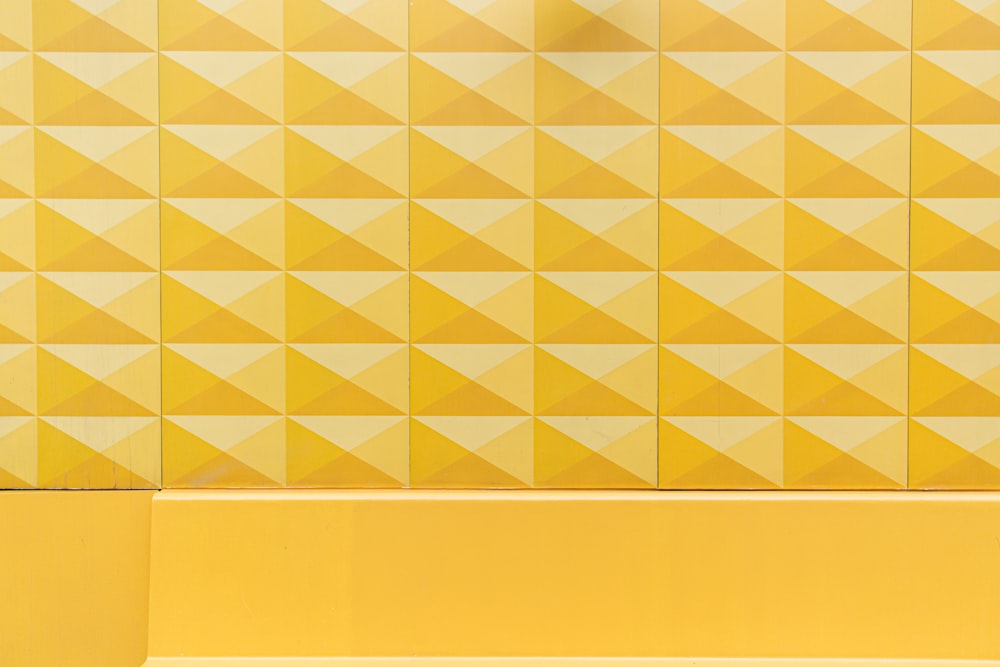 una persona seduta su una panchina di fronte a un muro giallo