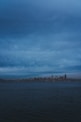 city buildings near body of water under cloudy sky