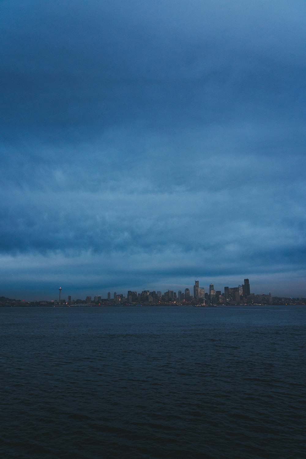 city buildings near body of water under cloudy sky