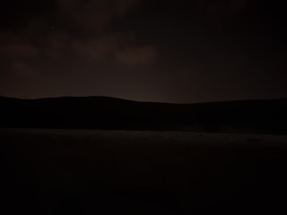 A cinematic landscape with a black sky and faint gold horizon glow.