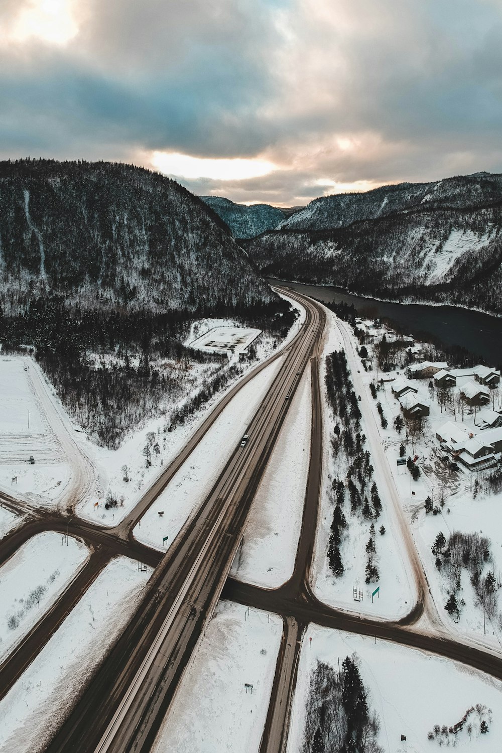 road near river and mountain covered with snow during daytime