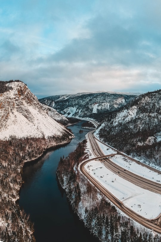 road near river and mountain covered with snow during daytime in Newfoundland Canada