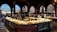 A bustling indoor seafood market with a large display of fresh fish and seafood on ice, surrounded by decorative arches and dim lighting. The architecture has an old-world charm with intricate stonework and a view of historic buildings through the windows.