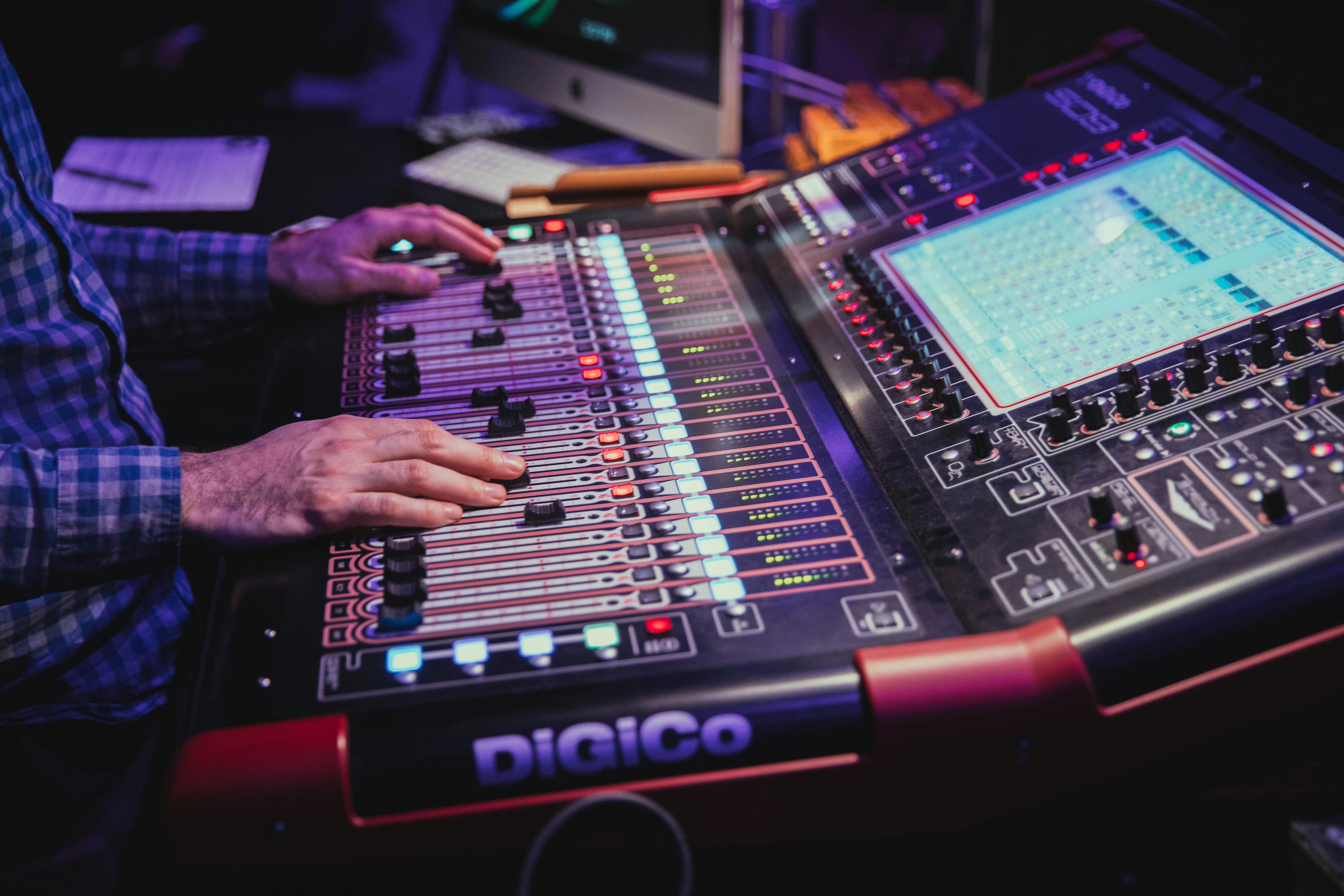 a man sitting at a mixing desk in front of a monitor