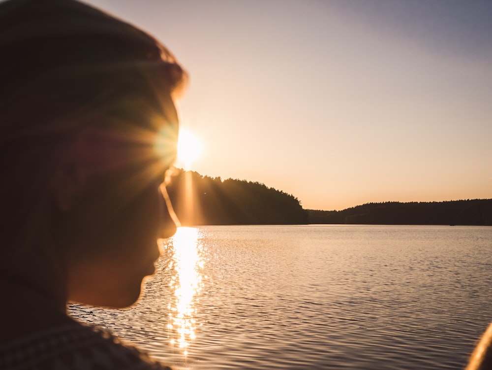 silhouette photography of person looking at the sea during golden hour