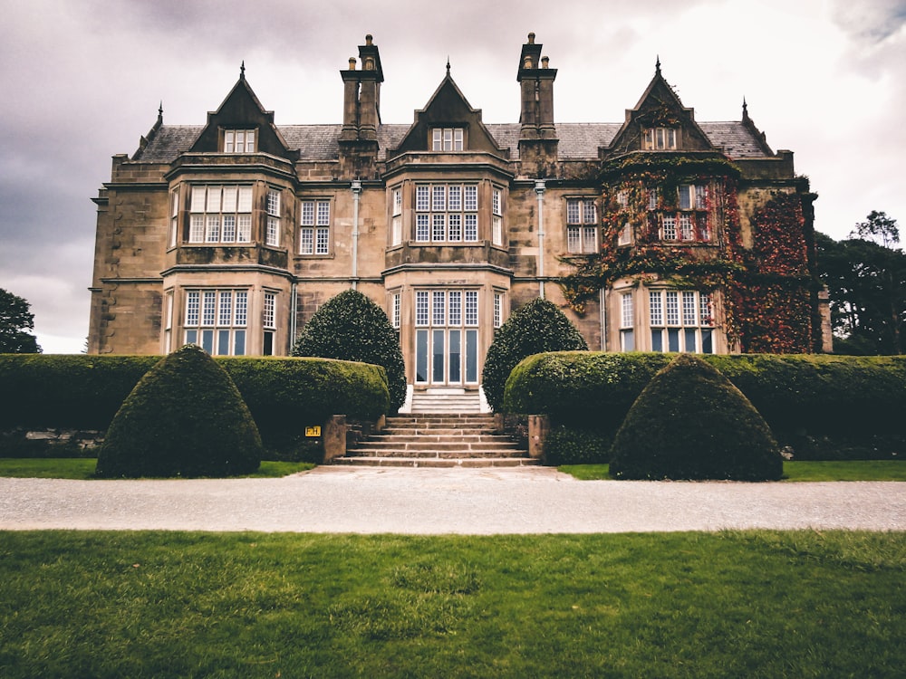 low-angle photography of brown mansion under a cloudy sky during daytime