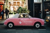 a pink car parked in front of a store