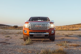 red Isuzu pickup truck under a calm blue sky