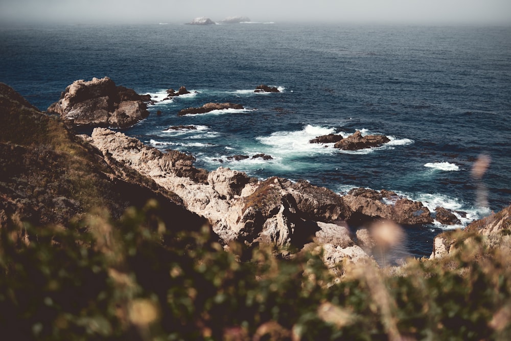 aerial photography of waves splashing on rocks in the sea