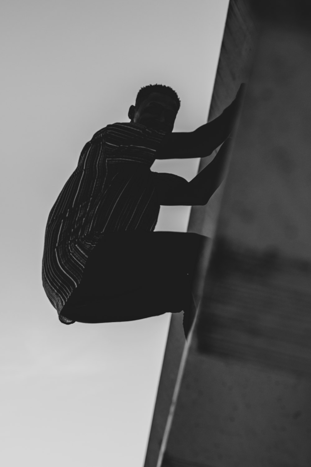 grayscale photography of man hanging from a wall