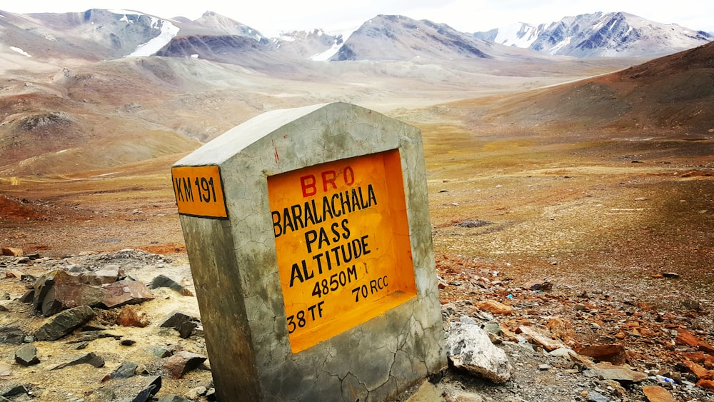 a sign on a rock in the middle of a mountain range