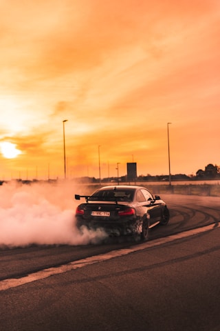 black car drifting on road during day