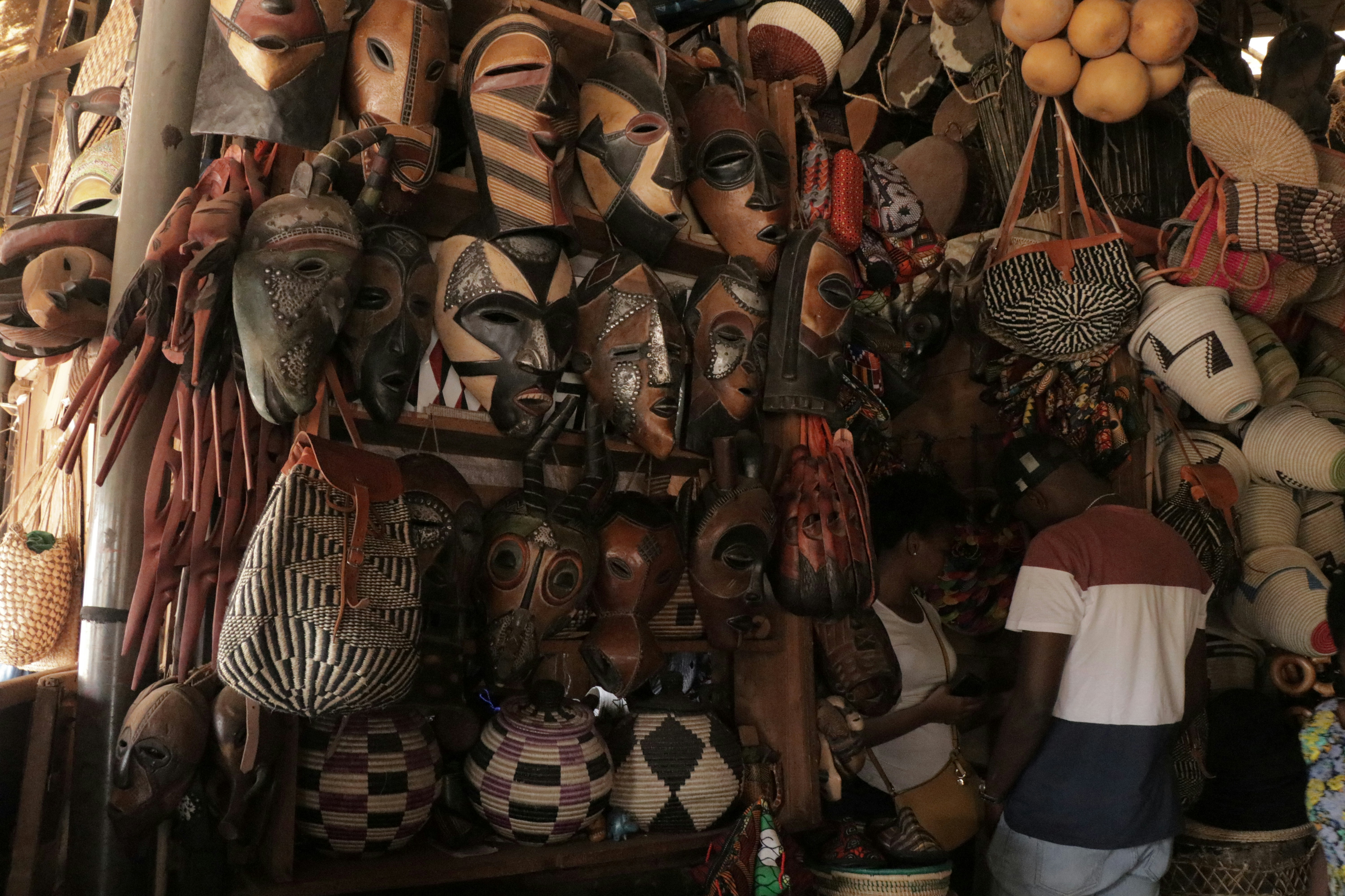Colorful African craft market stall with wooden sculptures and woven baskets