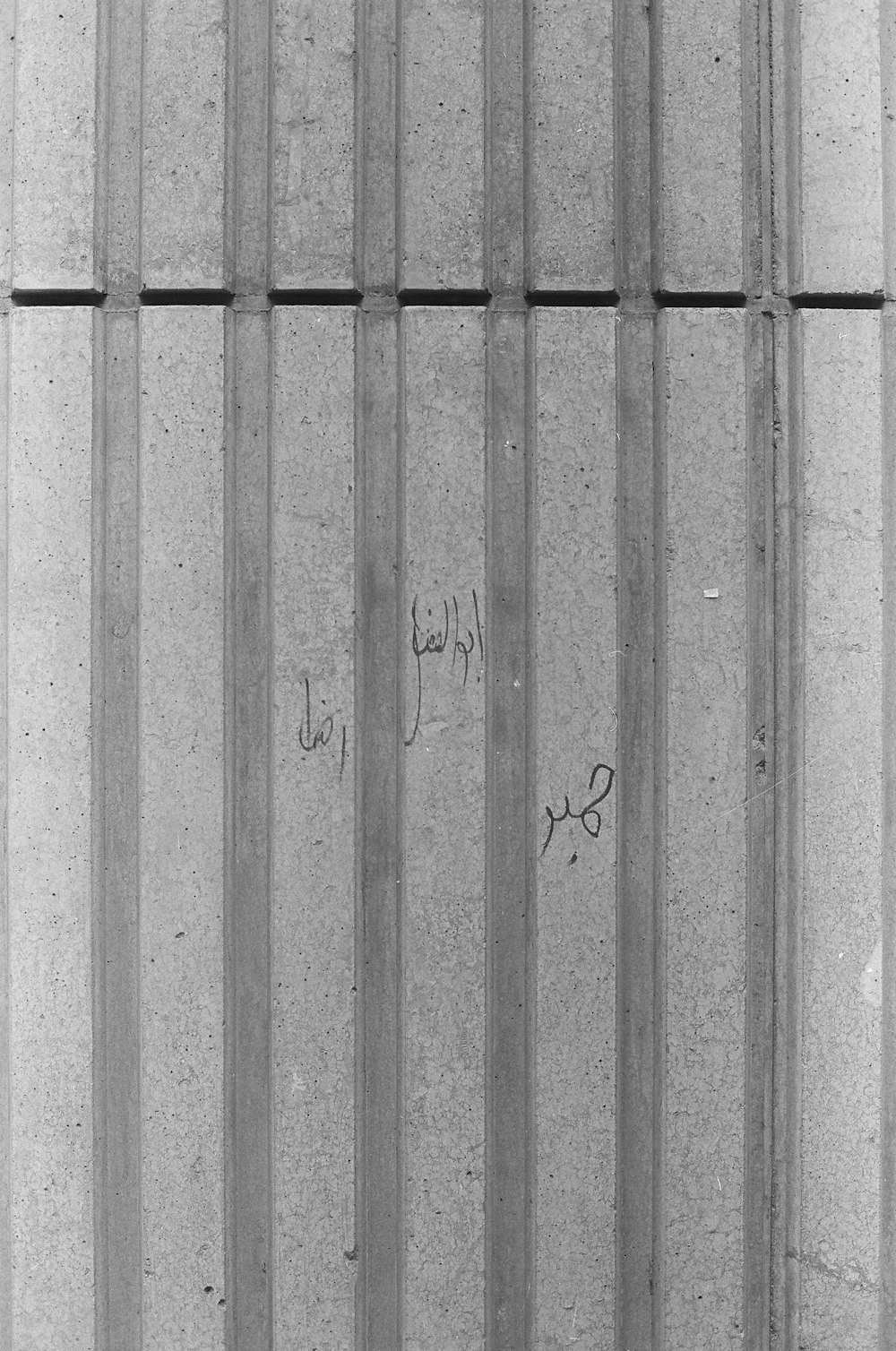 a black and white photo of a wall with writing on it
