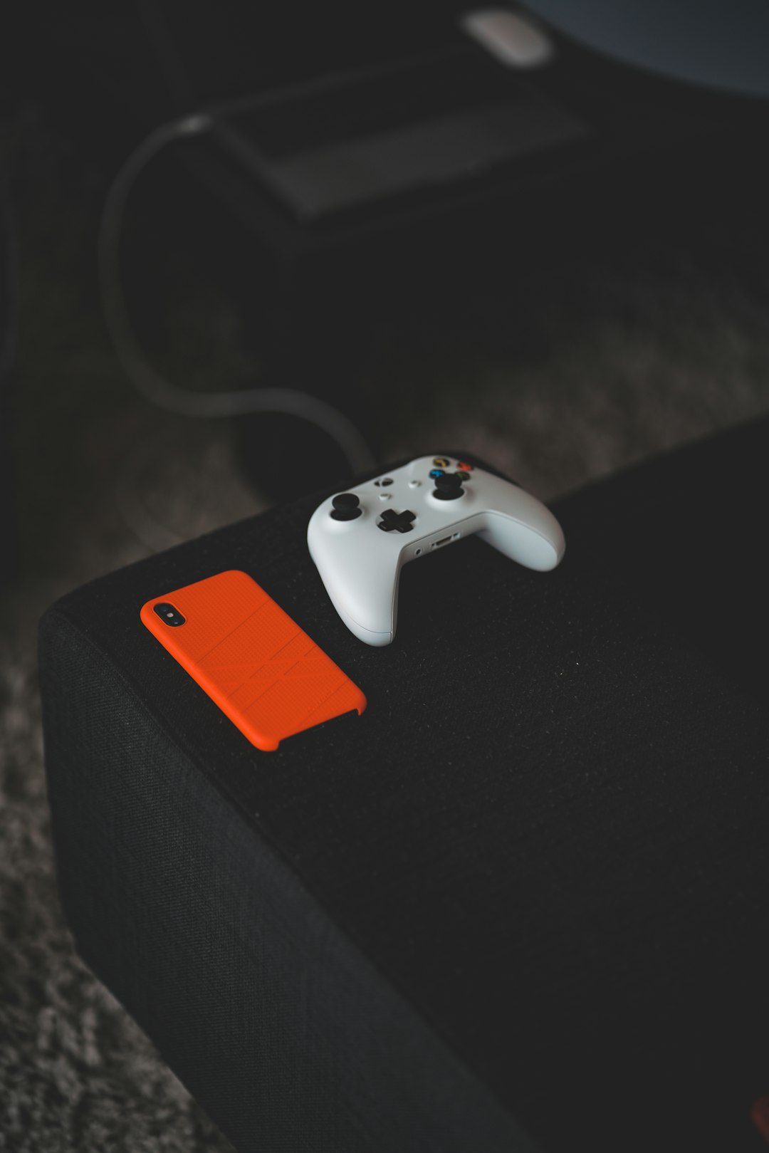 white Xbox One controller near orange iPhone X case