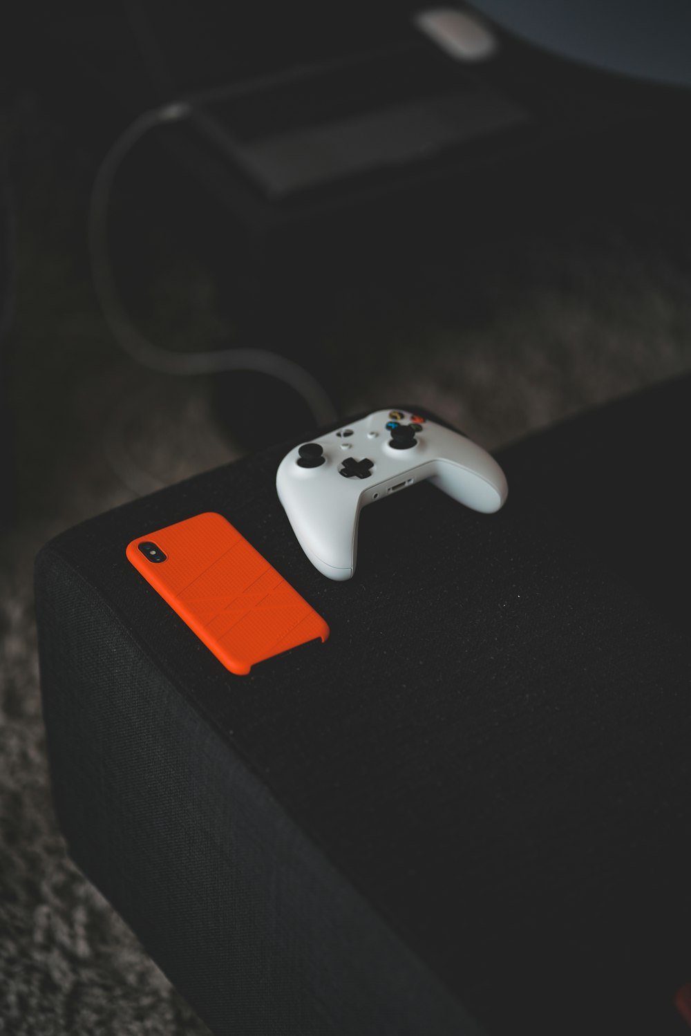 white Xbox One controller near orange iPhone X case