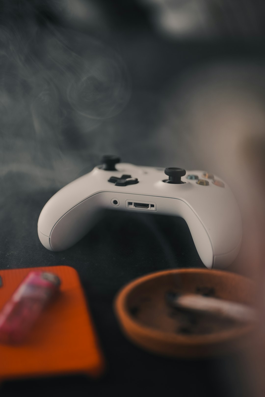 white Microsoft game controller beside orange ashtray