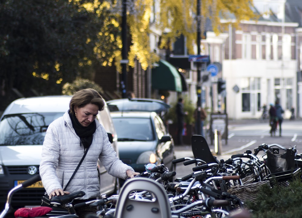 woman parking a bicycle on the side of street