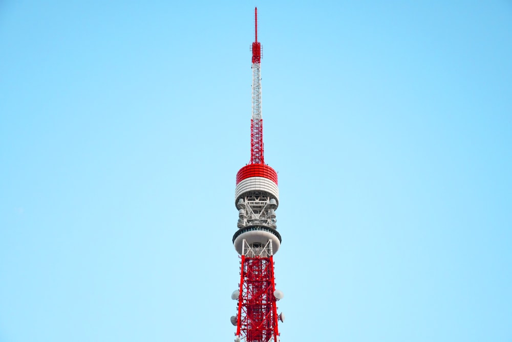 Photographie en contre-plongée d’une tour rouge et blanche sous un ciel bleu calme