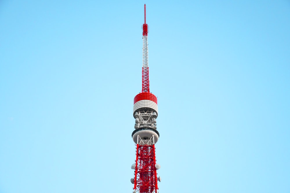 low-angle photography of a red and white tower under a calm blue sky