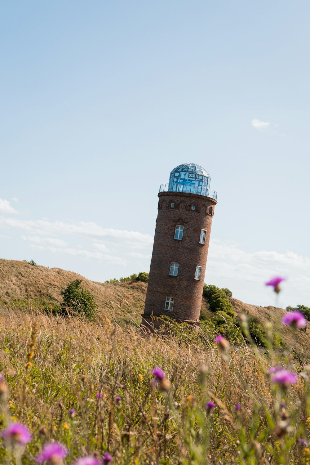 brown lighthouse on brown field under blue and white sky