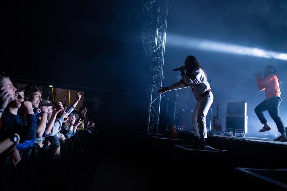 two people performing on stage near people