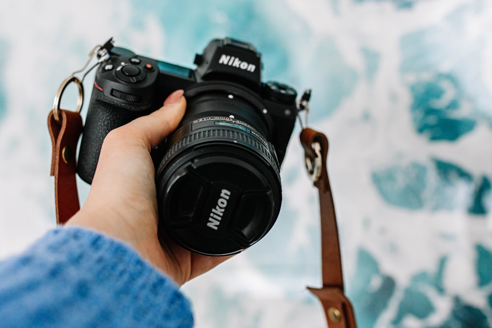 person holding black Nikon DSLR camera