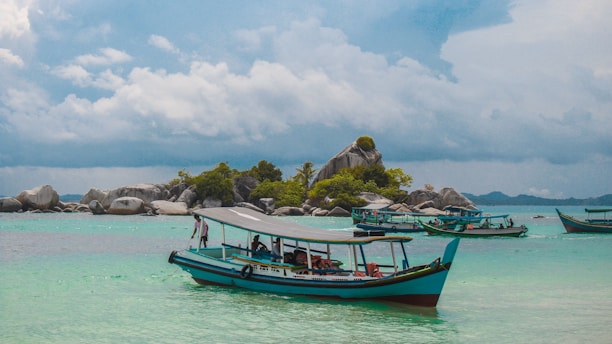 boats on body of water viewing island under white and blue sky