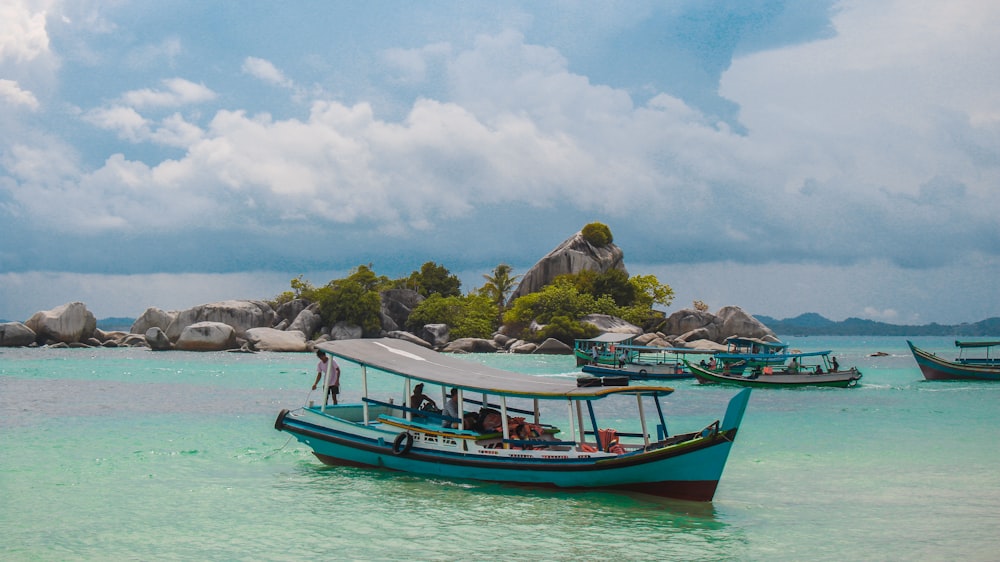 boats on body of water viewing island under white and blue sky