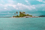 body of water viewing island under white and blue sky