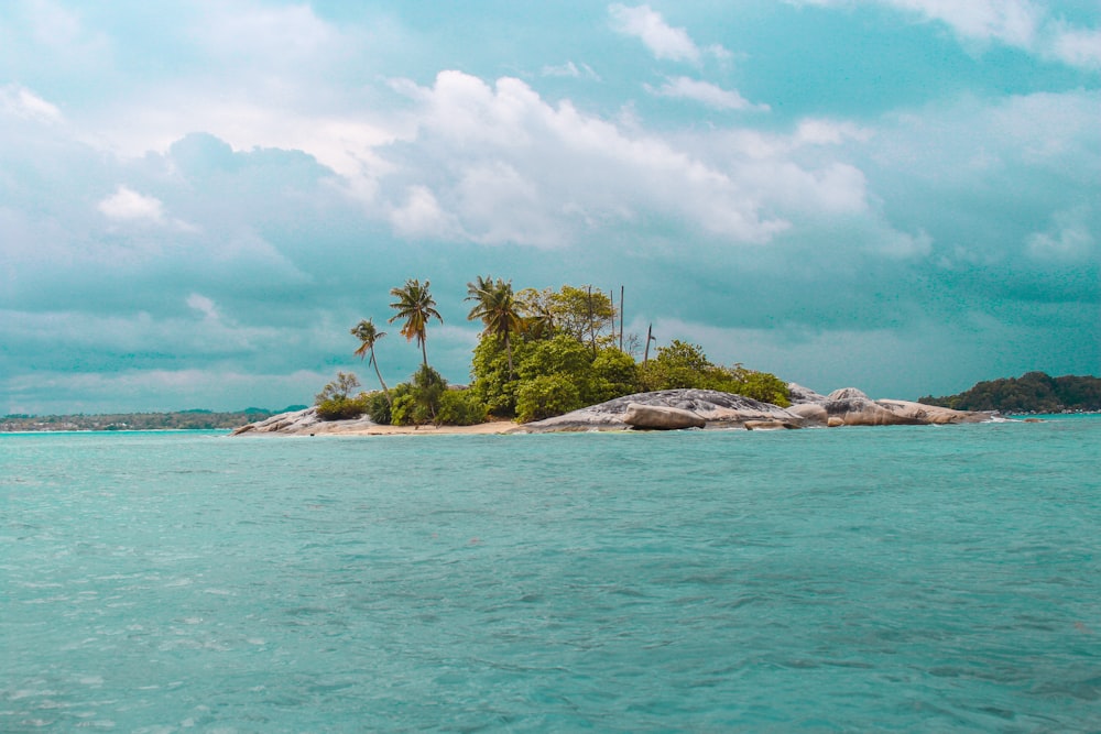 body of water viewing island under white and blue sky