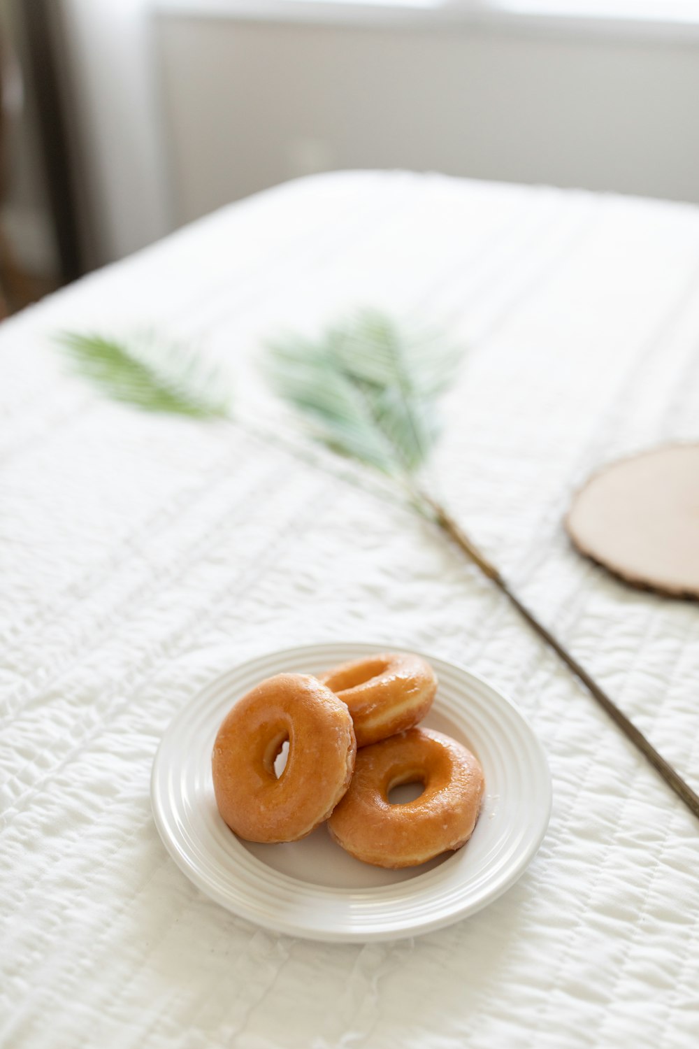 three donut on round white ceramic plate on a table